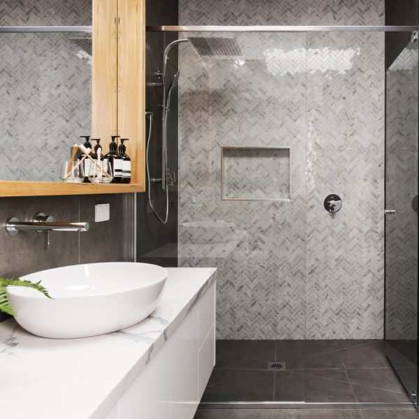 A glass shower enclosure that features black and white tiled walls