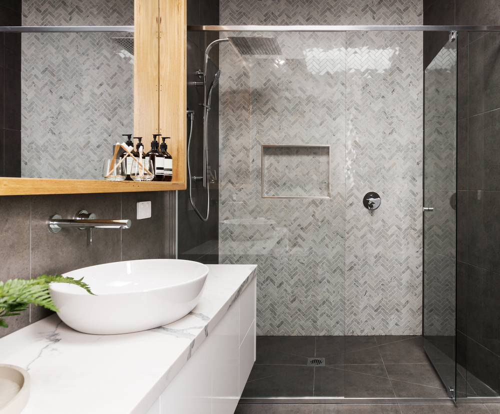 A glass shower enclosure that features black and white tiled walls